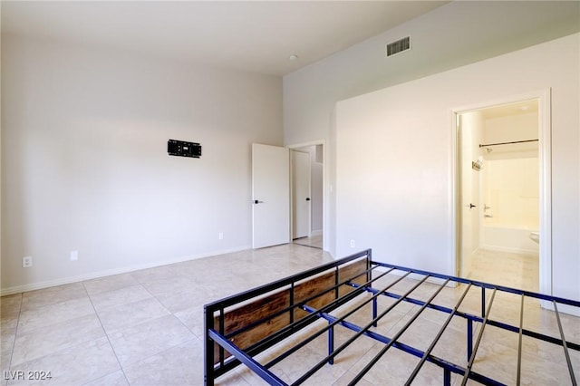 bedroom with light tile patterned floors and ensuite bath