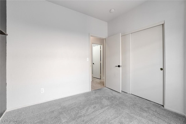 unfurnished bedroom featuring light carpet and a closet