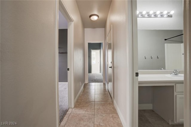 hallway with light tile patterned floors and sink