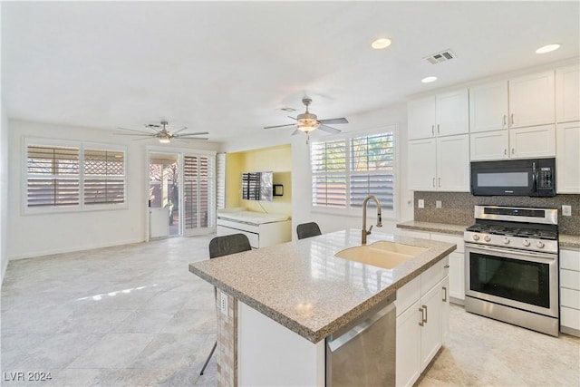 kitchen featuring stainless steel appliances, a kitchen island with sink, backsplash, white cabinetry, and sink