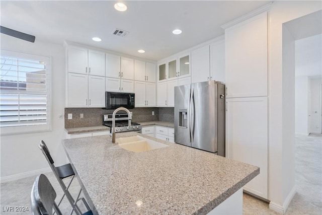 kitchen featuring light stone countertops, appliances with stainless steel finishes, backsplash, and white cabinetry