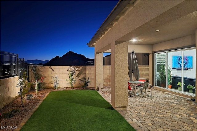 yard at night featuring a mountain view and a patio