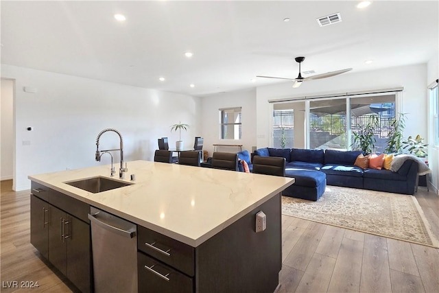 kitchen with dishwasher, sink, dark brown cabinetry, a center island with sink, and light wood-type flooring