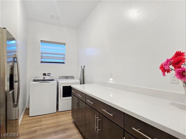 laundry room featuring cabinets, washer and dryer, and light hardwood / wood-style flooring