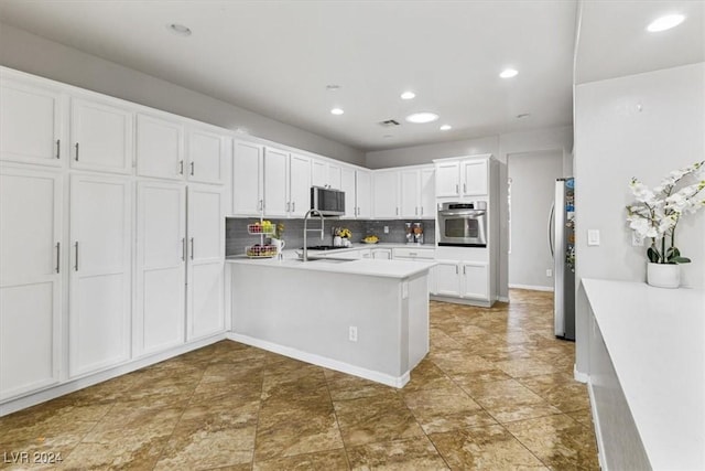 kitchen with white cabinetry, sink, stainless steel appliances, kitchen peninsula, and decorative backsplash