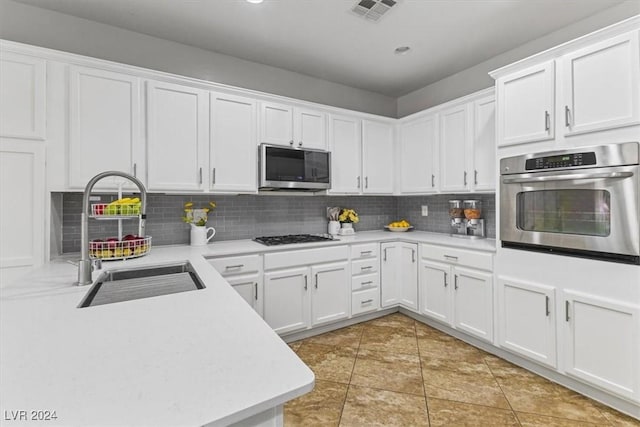 kitchen featuring white cabinets, sink, decorative backsplash, light tile patterned floors, and appliances with stainless steel finishes