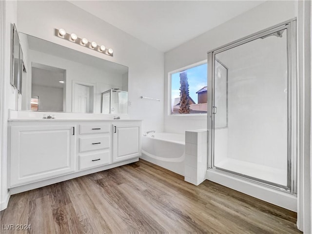 bathroom with hardwood / wood-style floors, vanity, and independent shower and bath