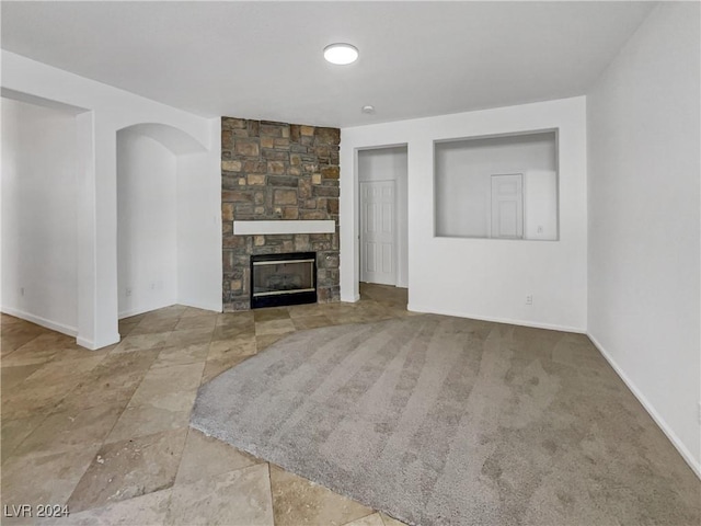 unfurnished living room with carpet and a stone fireplace