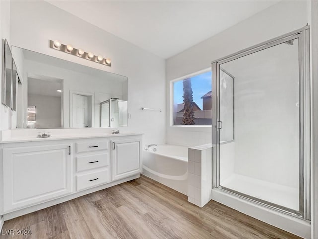 bathroom with hardwood / wood-style floors, vanity, and shower with separate bathtub