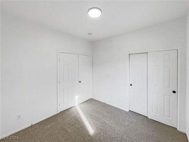 unfurnished bedroom with carpet and two closets