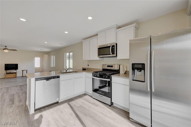 kitchen with kitchen peninsula, stainless steel appliances, sink, white cabinets, and light hardwood / wood-style floors