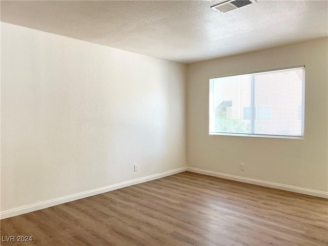 empty room featuring a textured ceiling and hardwood / wood-style flooring