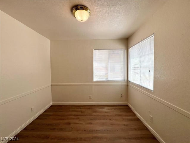 empty room with a textured ceiling and dark wood-type flooring