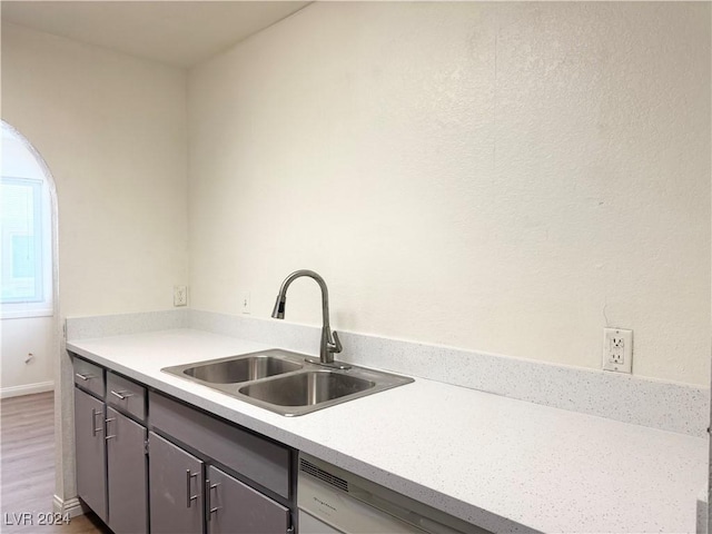 kitchen with dishwashing machine, sink, and hardwood / wood-style flooring