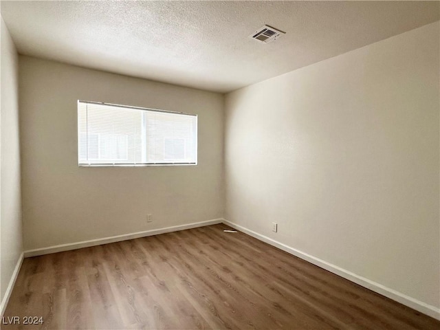 empty room featuring a textured ceiling and hardwood / wood-style flooring