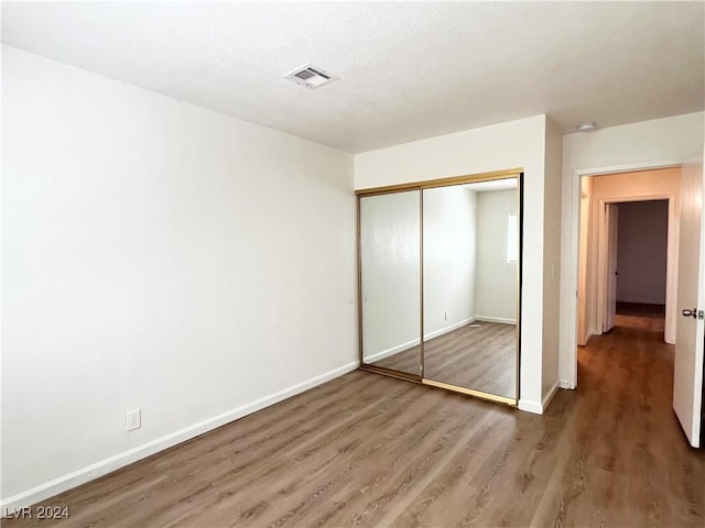 unfurnished bedroom featuring dark hardwood / wood-style flooring and a closet