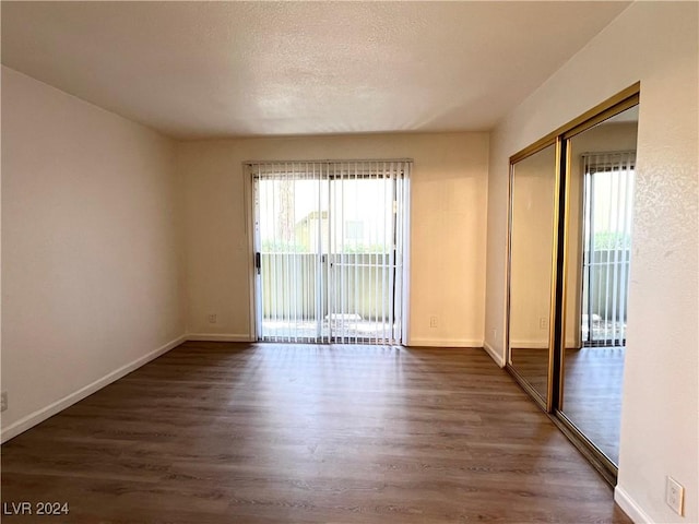 unfurnished room with dark hardwood / wood-style flooring and a textured ceiling