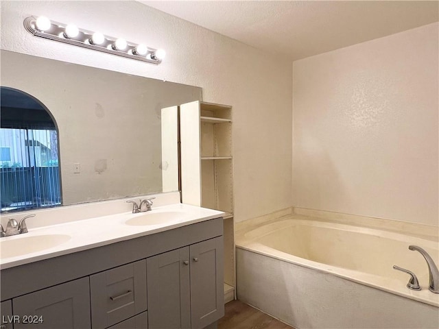 bathroom with hardwood / wood-style flooring, vanity, a tub to relax in, and a textured ceiling