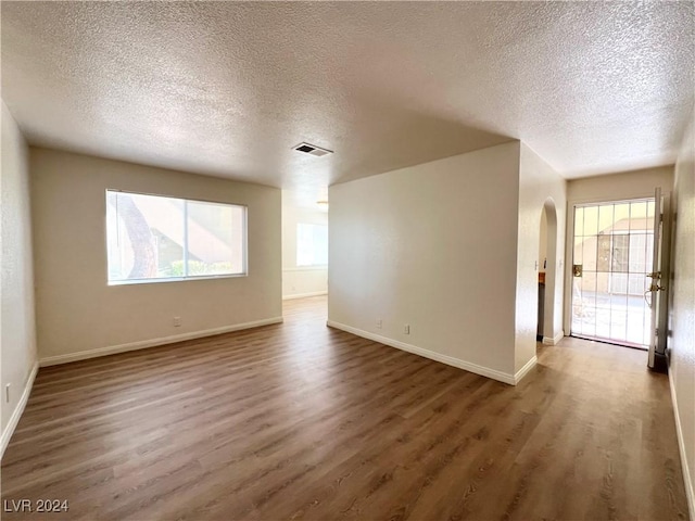 empty room with a textured ceiling and dark hardwood / wood-style flooring