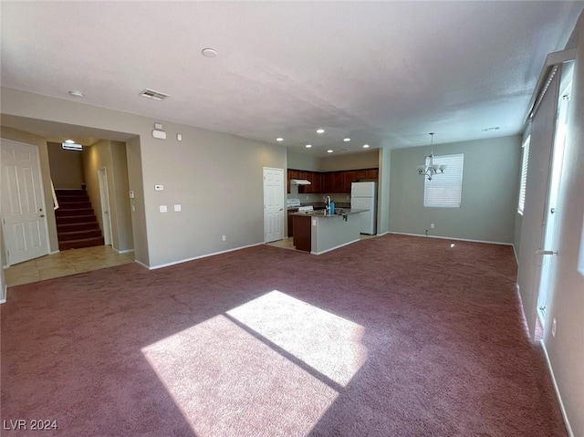 unfurnished living room with dark carpet, sink, and a chandelier