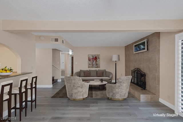 living room with a tiled fireplace and hardwood / wood-style floors