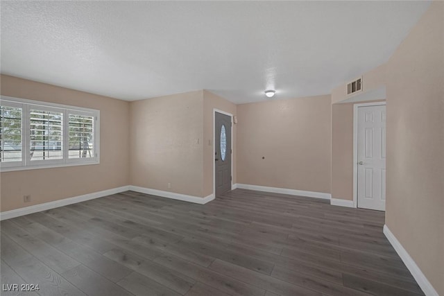 spare room featuring a textured ceiling and dark wood-type flooring