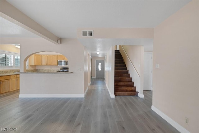 unfurnished living room featuring light hardwood / wood-style floors and beam ceiling