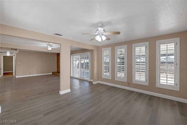 unfurnished room with wood-type flooring, a textured ceiling, and a wealth of natural light