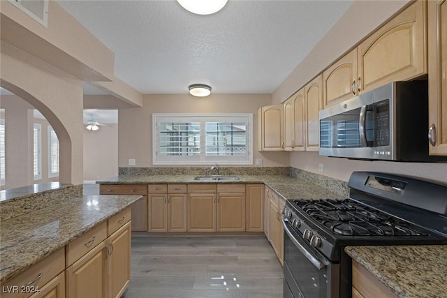 kitchen featuring sink, light brown cabinetry, light hardwood / wood-style floors, and appliances with stainless steel finishes