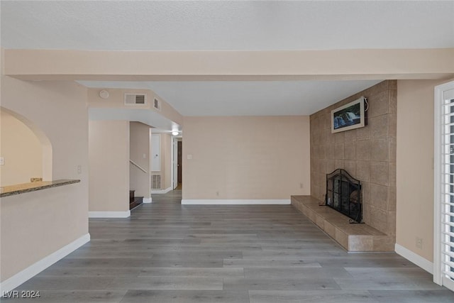 unfurnished living room featuring a tile fireplace and wood-type flooring