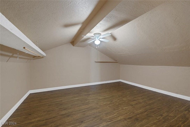 additional living space with lofted ceiling with beams, ceiling fan, dark wood-type flooring, and a textured ceiling