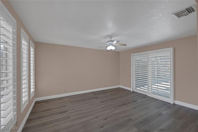 spare room with a textured ceiling, a wealth of natural light, ceiling fan, and dark hardwood / wood-style floors