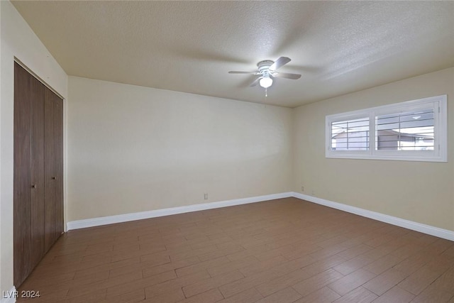 empty room with a textured ceiling, dark hardwood / wood-style floors, and ceiling fan