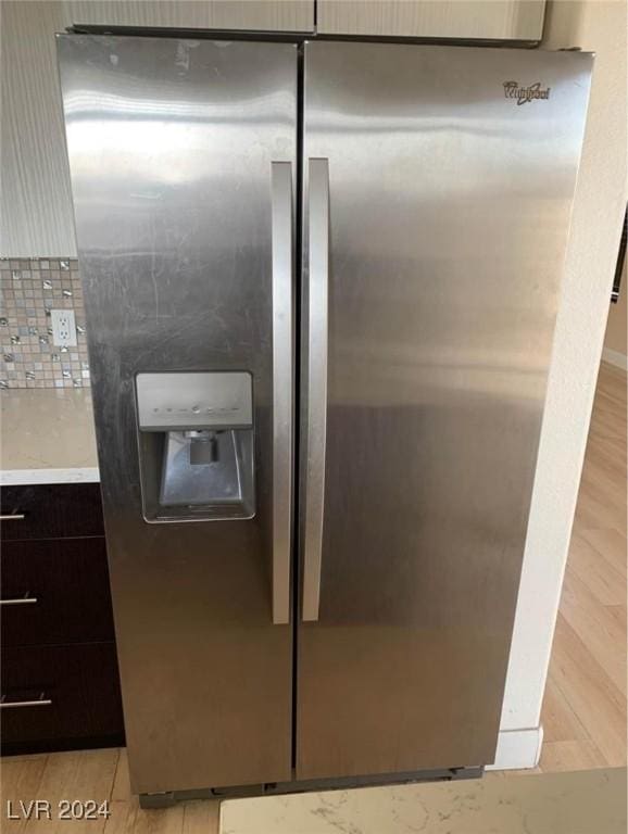 room details with dark brown cabinets, stainless steel fridge, and light hardwood / wood-style floors