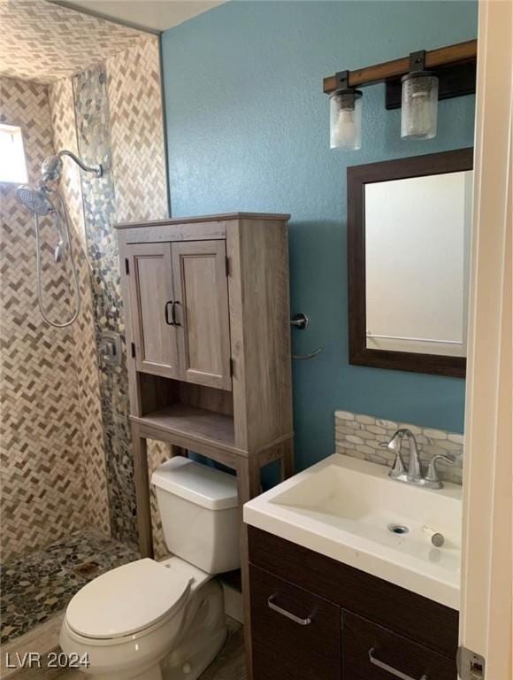 bathroom featuring a tile shower, vanity, and toilet