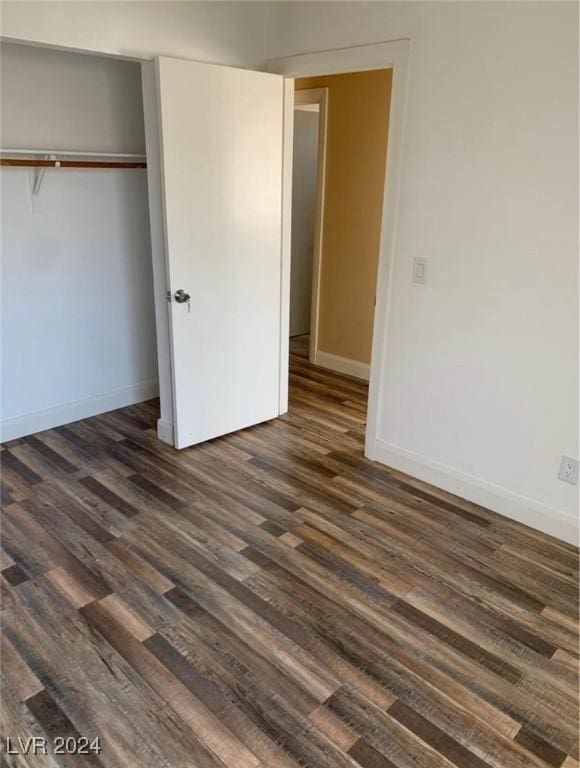 unfurnished bedroom with a closet and dark wood-type flooring