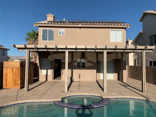 rear view of property with a patio and a pool with hot tub