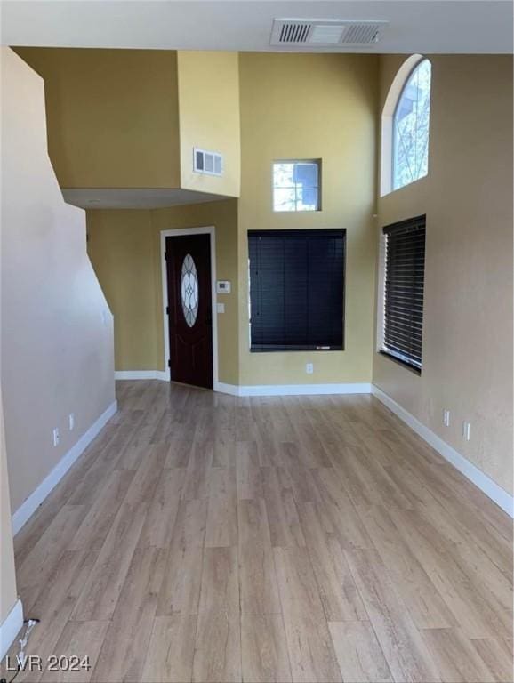 foyer entrance featuring a towering ceiling and light hardwood / wood-style floors