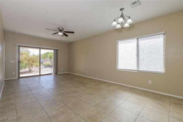 tiled empty room with ceiling fan with notable chandelier