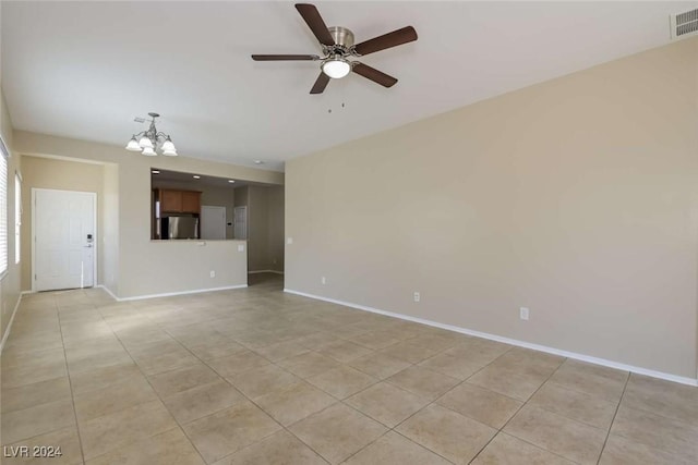 unfurnished room with ceiling fan with notable chandelier and light tile patterned floors