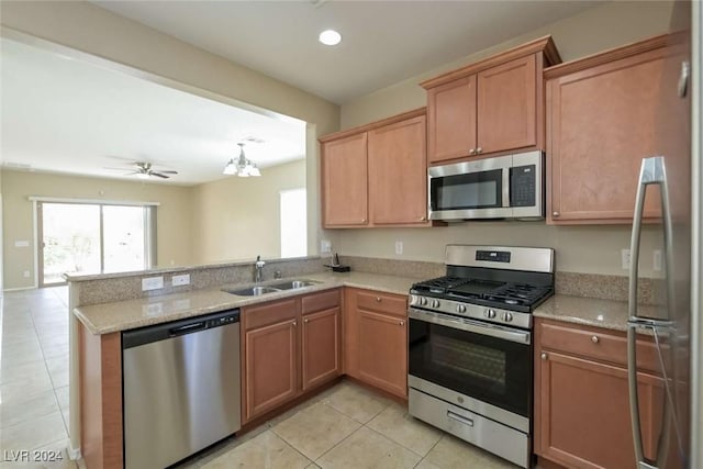 kitchen with sink, kitchen peninsula, light tile patterned flooring, ceiling fan with notable chandelier, and appliances with stainless steel finishes