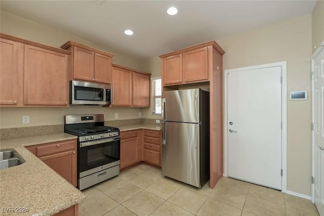 kitchen featuring light stone countertops, light tile patterned floors, sink, and appliances with stainless steel finishes