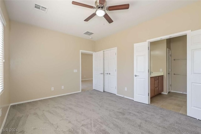 unfurnished bedroom with ceiling fan, ensuite bathroom, and light carpet