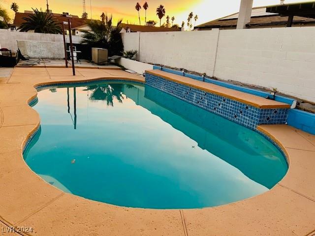 pool at dusk featuring a patio area