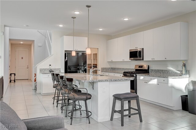 kitchen featuring a kitchen breakfast bar, sink, appliances with stainless steel finishes, decorative light fixtures, and white cabinetry