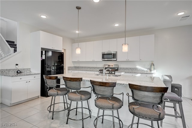 kitchen with sink, decorative light fixtures, light tile patterned flooring, white cabinetry, and stainless steel appliances