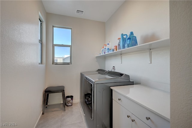 laundry room featuring cabinets, light tile patterned floors, and separate washer and dryer