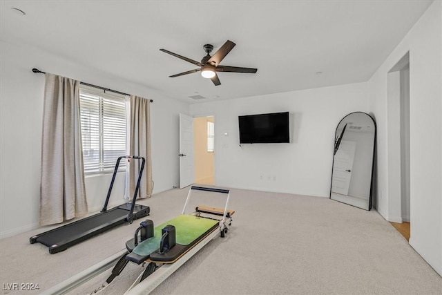 workout area featuring ceiling fan and light colored carpet