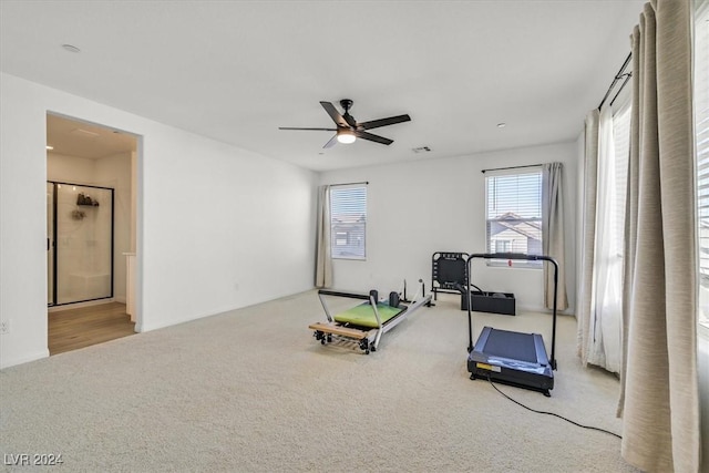 exercise room with light colored carpet and ceiling fan