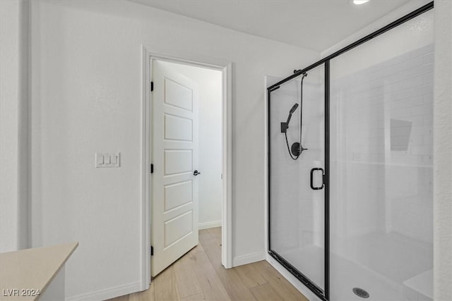 bathroom featuring a shower with shower door and hardwood / wood-style flooring